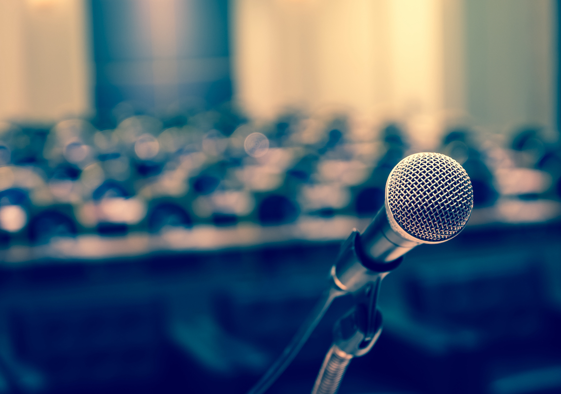 Microphone,Over,The,Abstract,Blurred,Photo,Of,Conference,Hall,Or